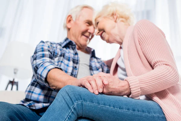 Selective focus of happy senior couple looking at each other and holding hands — Stock Photo