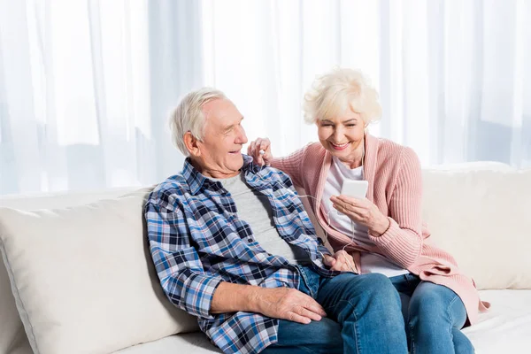 Feliz pareja de ancianos en auriculares escuchando música juntos en casa - foto de stock