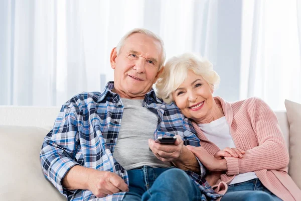 Seniorenpaar mit Fernbedienung vor dem Fernseher auf der Couch — Stockfoto