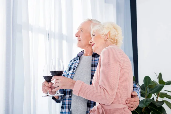 Porträt einer glücklichen Seniorin und ihres Mannes mit einem Glas Rotwein zu Hause — Stockfoto