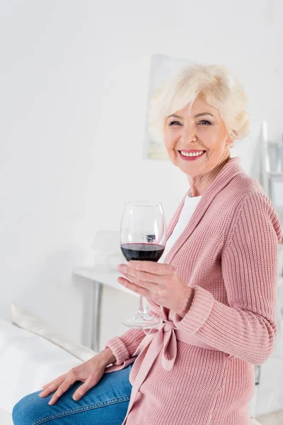 Retrato de bela mulher sênior feliz com copo de vinho tinto em casa — Fotografia de Stock