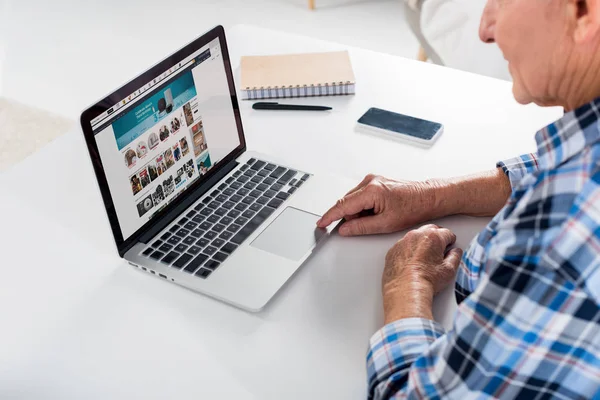 Vista parziale di uomo anziano seduto a tavola e utilizzando il computer portatile — Foto stock