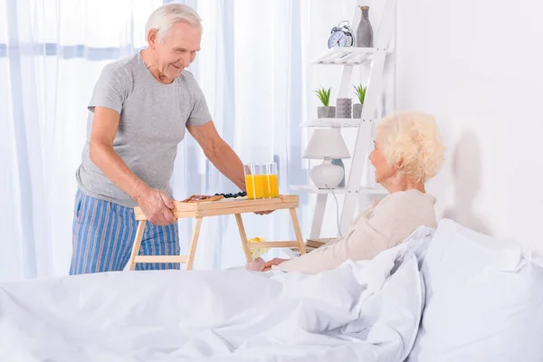 Senior man brought breakfast in bed for wife in morning at home — Stock Photo