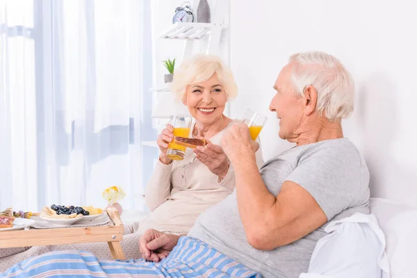 Heureux couple de personnes âgées prenant le petit déjeuner au lit ensemble à la maison — Photo de stock