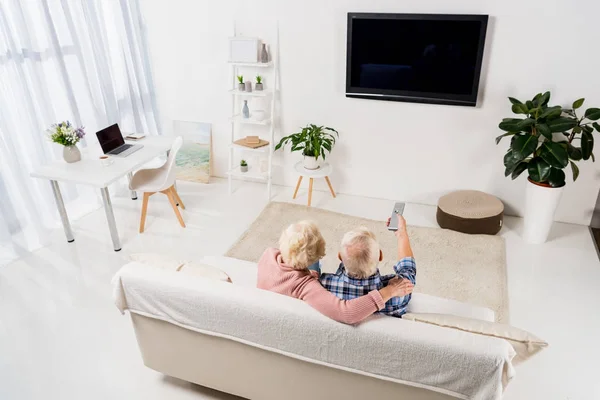 Anziani coppia guardando la televisione su accogliente divano a casa — Foto stock