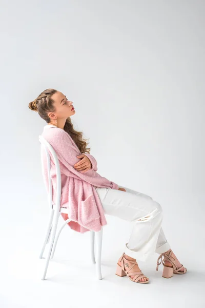 Fille fatiguée assise sur une chaise blanche avec les yeux fermés sur blanc — Photo de stock