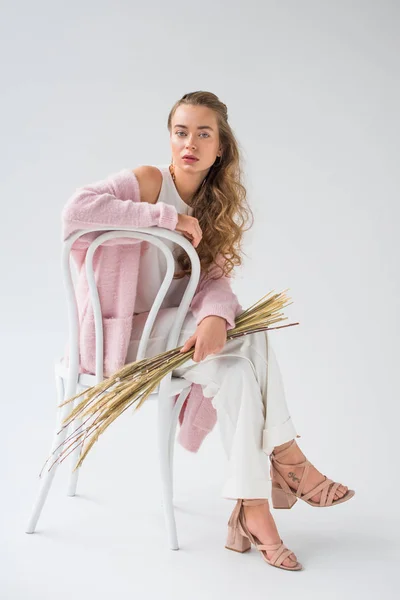 Beautiful girl sitting and holding bunch of willow tree branches on white — Stock Photo