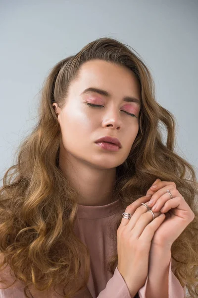 Portrait of beautiful girl with makeup and rings with closed eyes isolated on gray — Stock Photo