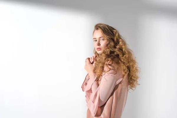 Chica confundida en vestido beige con el pelo rizado mirando a la cámara — Stock Photo