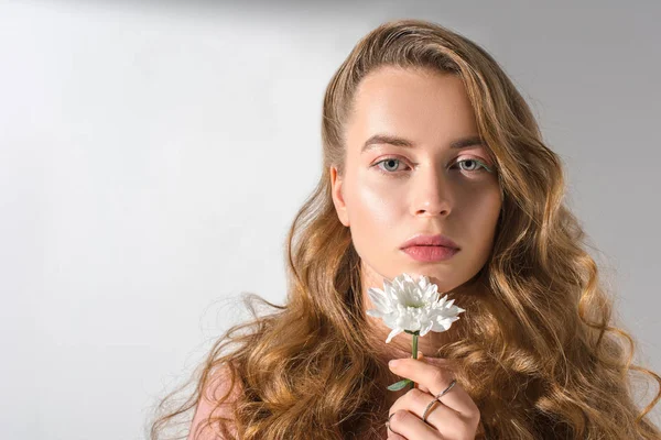 Ritratto di bella ragazza seria in possesso di fiore bianco e guardando la fotocamera — Foto stock