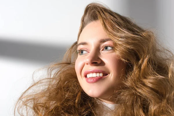 Портрет усміхненої дівчини з кучерявим волоссям, що дивиться вдалину — стокове фото