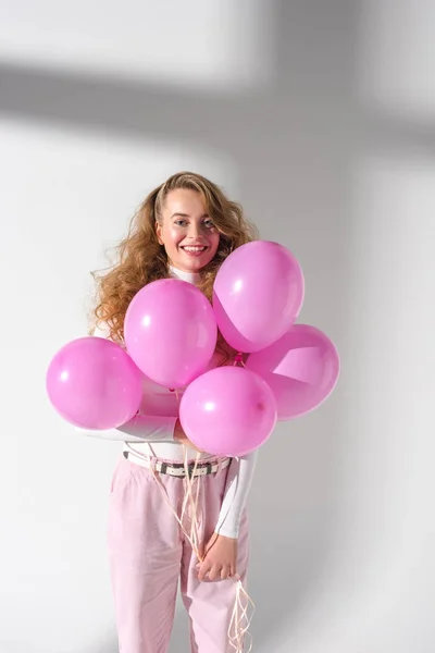 Femme gaie debout et tenant cinq ballons roses — Photo de stock