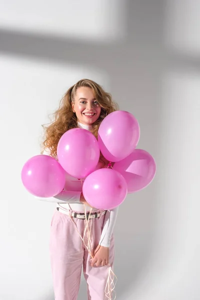 Cheerful woman standing and holding five pink balloons — Stock Photo