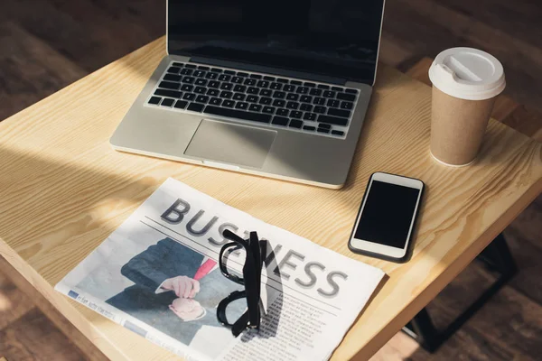 Кава-брейк з ноутбуком, смартфоном і бізнес-газетою на столі в кав'ярні — стокове фото