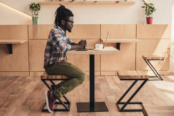 Homme afro-américain en utilisant un ordinateur portable dans un café — Photo de stock