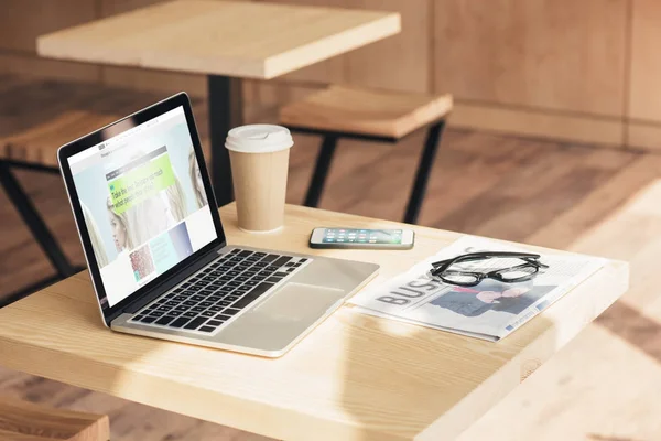 Ноутбук з Бі-Бі-веб-сайт, смартфон і бізнес газетою на стіл в кафе — стокове фото
