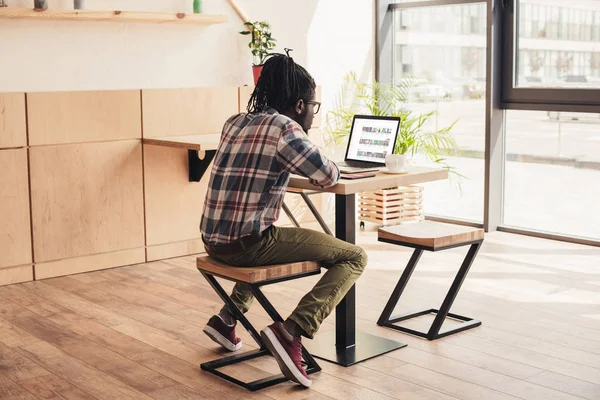 Back view of african american man using laptop with youtube website in coffee shop — Stock Photo