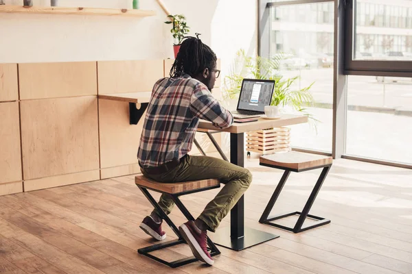 Vista posterior del hombre afroamericano utilizando el ordenador portátil con linkedin sitio web en la cafetería - foto de stock