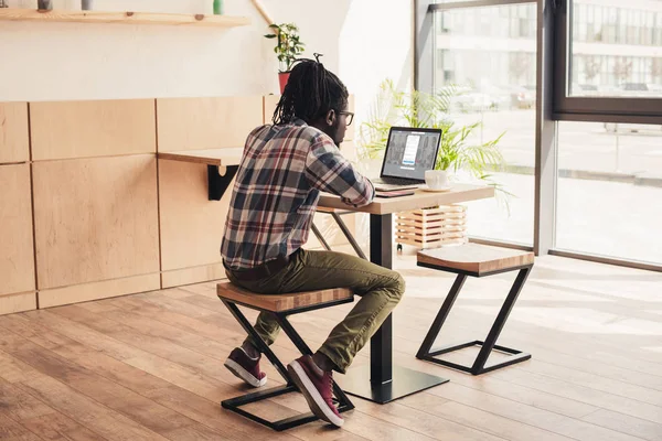 Back view of african american man using laptop with linkedin website in coffee shop — Stock Photo