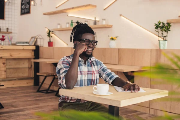 Afro-américain parler sur smartphone et boire du café dans le café — Photo de stock