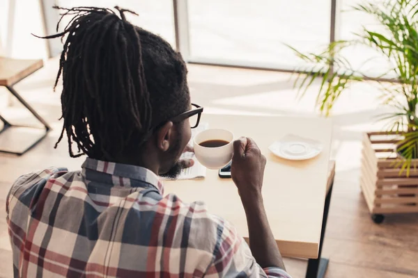 Vue arrière de l'homme afro-américain buvant du café aromatique dans le café — Photo de stock