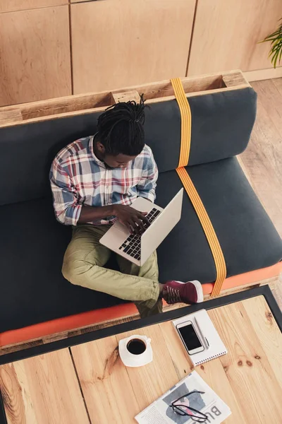 Vista aérea del hombre afroamericano utilizando el ordenador portátil en la cafetería - foto de stock