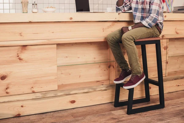 Low section of african american man sitting at bar counter in cafe — Stock Photo