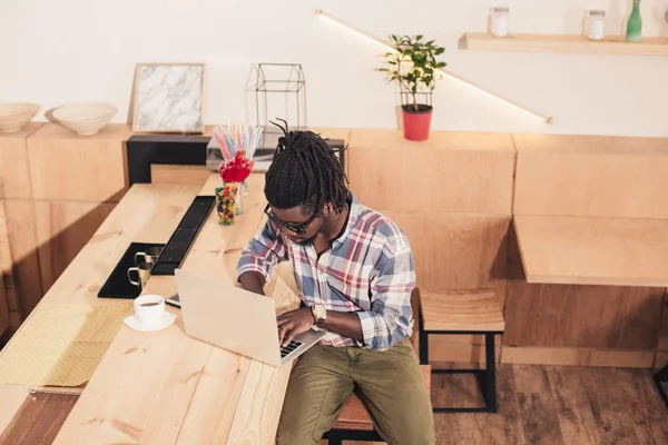 Афроамериканський чоловік використовує ноутбук на барній стійці в кав'ярні — стокове фото