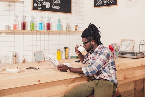 Afro-américain boire du café et lire un journal d'affaires — Photo de stock