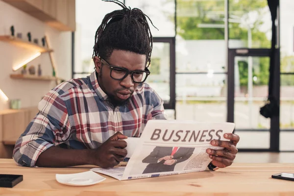 Konzentrierter afrikanisch-amerikanischer Mann trinkt Kaffee und liest Wirtschaftszeitung — Stockfoto