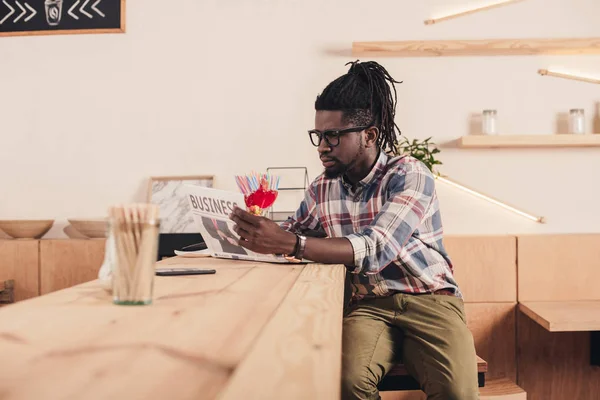 African american man reading business newspaper while sitting at bar counter — Stock Photo