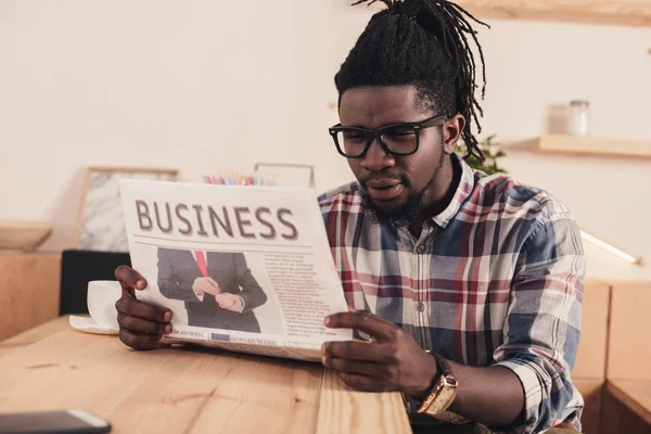 Концентрований афроамериканський чоловік читає бізнес-газету в кафе — стокове фото