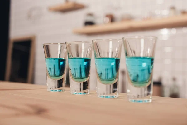 Primer plano de cócteles azules en vasos de chupito de pie en el mostrador del bar - foto de stock