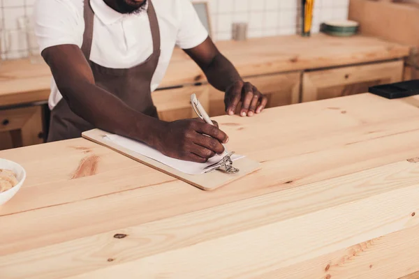 Geschnittene Ansicht eines afrikanisch-amerikanischen Baristas, der an der Theke Ordnung schafft — Stockfoto