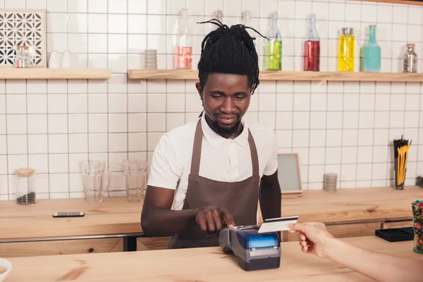 Barista afro-americano com leitor de cartão de crédito no balcão do bar — Fotografia de Stock