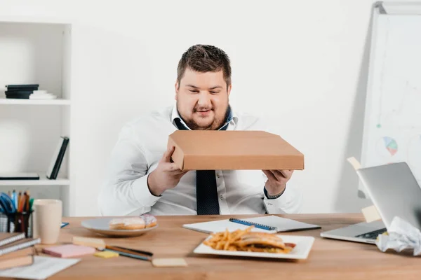 Übergewichtiger Geschäftsmann isst Pizza am Arbeitsplatz — Stockfoto