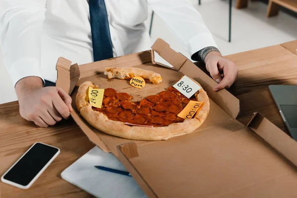 Visão cortada do excesso de peso empresário comer pizza no local de trabalho — Fotografia de Stock
