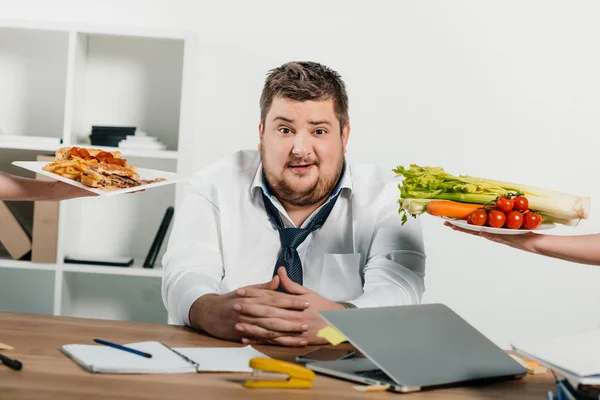 Overweight businessman choosing healthy or junk food at workplace in office — Stock Photo