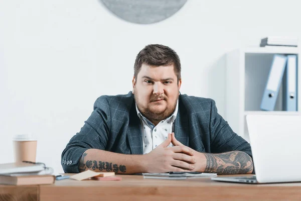 Selbstbewusster übergewichtiger Geschäftsmann sitzt im Büro am Arbeitsplatz — Stockfoto