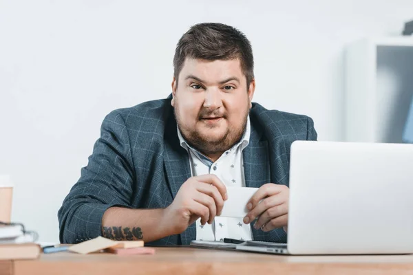 Hombre de negocios gordo en traje de trabajo con teléfono inteligente y portátil en el lugar de trabajo — Stock Photo