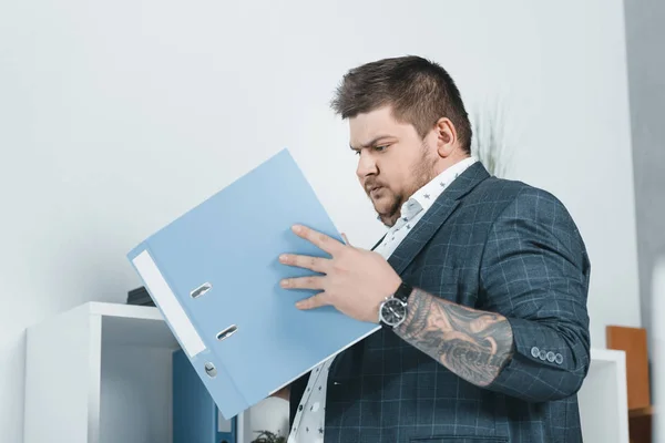 Hombre de negocios con sobrepeso en traje trabajando con documentos en carpetas - foto de stock