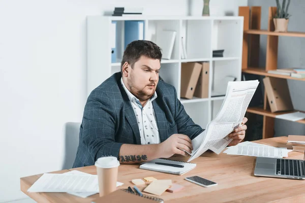 Dicker Geschäftsmann im Anzug liest Zeitung am Arbeitsplatz — Stockfoto