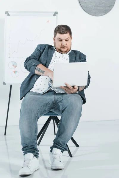 Hombre de negocios con sobrepeso en traje de trabajo con portátil en la oficina - foto de stock