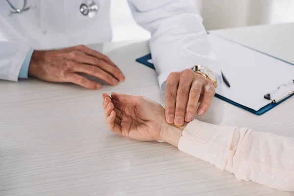 Imagem recortada do médico que mede o pulso fêmea do paciente — Fotografia de Stock