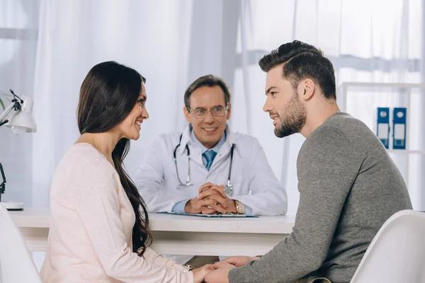 Happy couple holding hands at clinic and looking at each other — Stock Photo