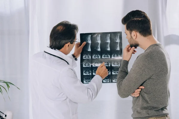 Doctor apuntando a la foto de rayos X del paciente masculino - foto de stock