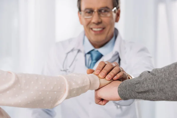 Cropped image of doctor and two patients holding hands — Stock Photo