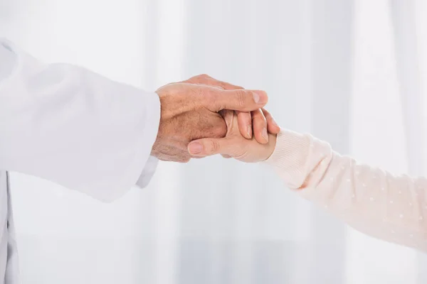 Imagen recortada del médico masculino sosteniendo la mano del paciente femenino - foto de stock