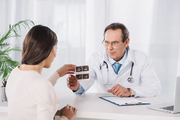 Médico varón mostrando mujer embarazada foto de diagnósticos de ultrasonido - foto de stock