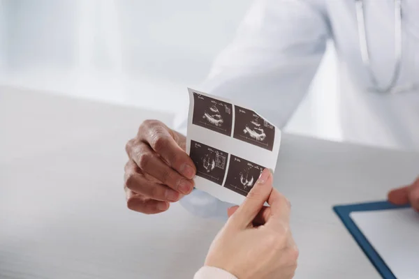 Imagen recortada del médico dando a la mujer embarazada foto de los diagnósticos de ultrasonido - foto de stock